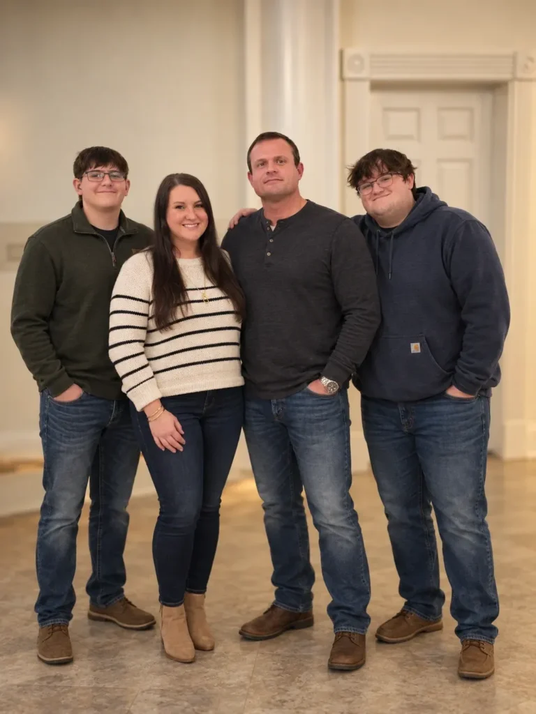 A family of four standing together for a photo, consisting of a woman and man flanked by two young men.